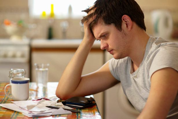 Worried-young-man-holding-his-head-while-looking-at-receipts
